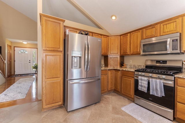 5 Tatiana Ct, Bloomington, IL 61704 - kitchen featuring appliances with stainless steel finishes, vaulted ceiling, light stone counters, brown cabinets, and light tile patterned flooring
