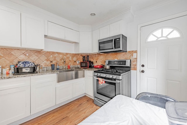 21 165th St, Calumet City, IL 60409 - kitchen with appliances with stainless steel finishes, white cabinetry, a sink, light stone counters, and crown molding
