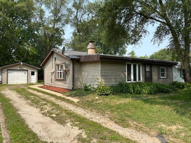 1904 Roberts St, Wilmington, IL 60481 - view of front facade featuring an outbuilding, dirt driveway, a garage, a chimney, and a front lawn
