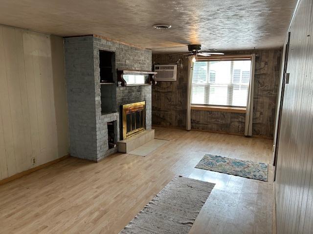 1904 Roberts St, Wilmington, IL 60481 - unfurnished living room featuring ceiling fan, a multi sided fireplace, wood finished floors, wooden walls, and a wall mounted air conditioner