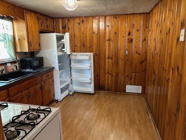 1904 Roberts St, Wilmington, IL 60481 - kitchen featuring range, brown cabinetry, a textured ceiling, light wood-style floors, and wooden walls