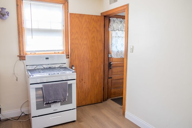 4948 S Lamon Ave, Chicago, IL 60638 - kitchen with white gas range, light wood-style flooring, and baseboards