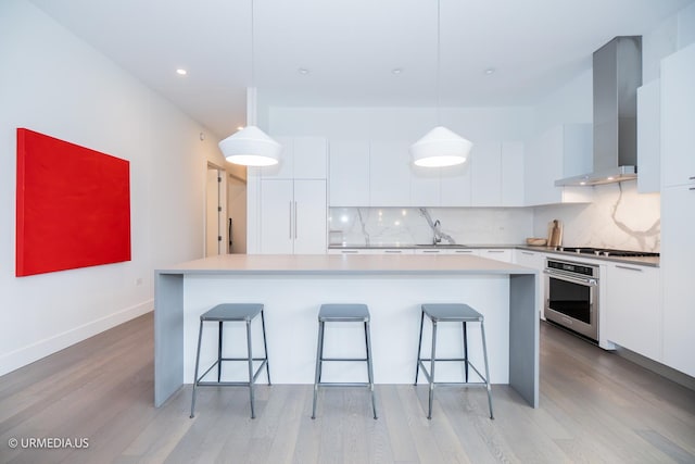 367 W Locust St Unit 202, Chicago, IL 60610 - kitchen featuring stainless steel appliances, wall chimney range hood, modern cabinets, light wood finished floors, and backsplash