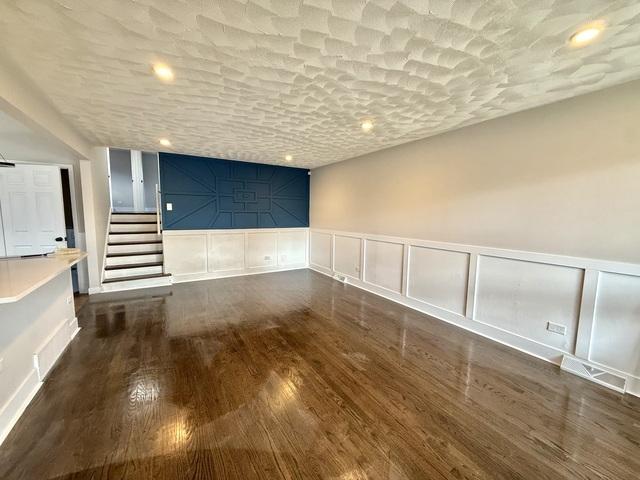 14409 Kimbark Ave, Dolton, IL 60419 - spare room with a decorative wall, wood finished floors, stairway, wainscoting, and recessed lighting