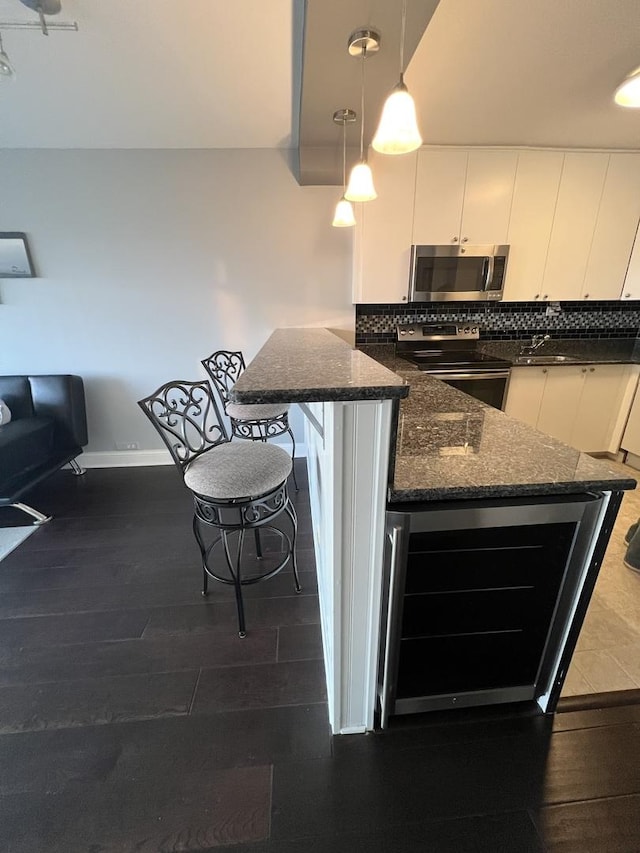 1850 N Clark St Unit 2106, Chicago, IL 60614 - kitchen featuring stainless steel appliances, white cabinets, decorative light fixtures, beverage cooler, and dark stone counters