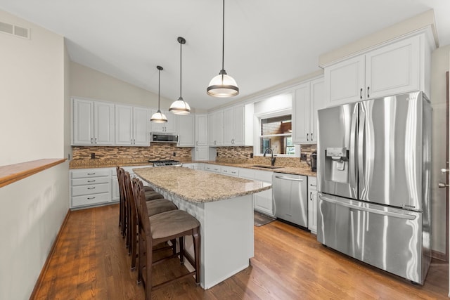 1527 62nd St, Downers Grove, IL 60516 - kitchen featuring appliances with stainless steel finishes, decorative backsplash, a kitchen island, white cabinets, and vaulted ceiling