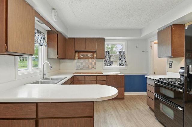 2236 Thornton Lansing Rd, Lansing, IL 60438 - kitchen featuring black gas range, a sink, a textured ceiling, light countertops, and light wood-style flooring