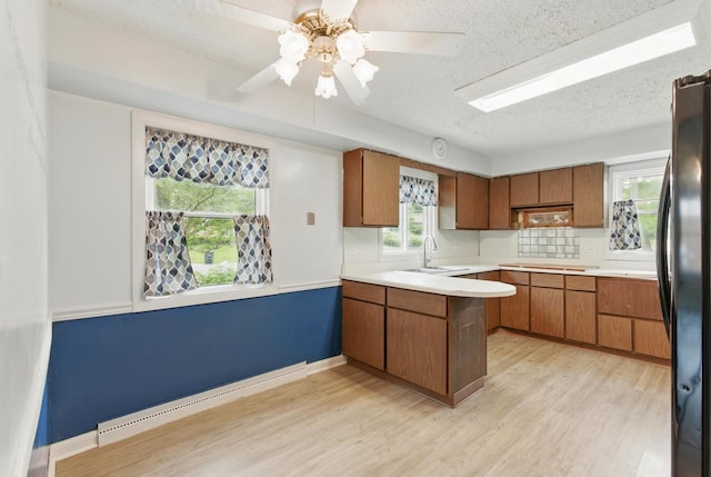 2236 Thornton Lansing Rd, Lansing, IL 60438 - kitchen featuring a baseboard heating unit, freestanding refrigerator, brown cabinetry, a peninsula, and a textured ceiling