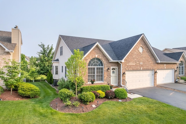 595 Sudbury Cir, Oswego, IL 60543 - view of front of house with brick siding, a front lawn, asphalt driveway, an attached garage, and a shingled roof