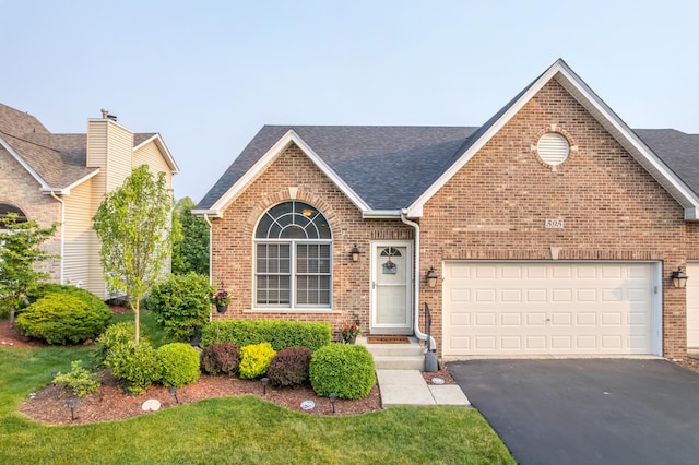 595 Sudbury Cir, Oswego, IL 60543 - view of front facade with brick siding, roof with shingles, asphalt driveway, and an attached garage