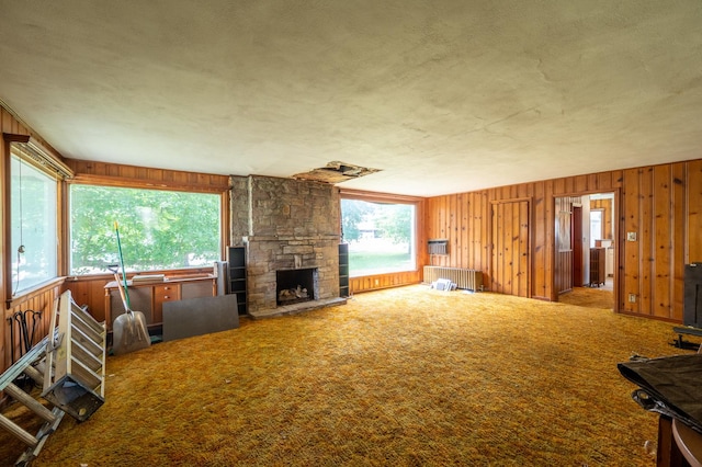 4 E Lincoln St, Mount Morris, IL 61054 - unfurnished living room with radiator heating unit, healthy amount of natural light, wooden walls, and a stone fireplace