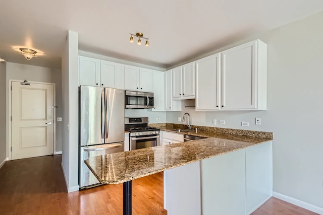 645 N Kingsbury St Unit 1203, Chicago, IL 60654 - kitchen featuring appliances with stainless steel finishes, stone countertops, white cabinetry, a peninsula, and wood finished floors