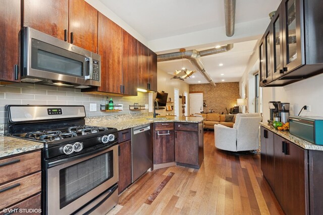 1956 W Bradley Pl Unit 2W, Chicago, IL 60613 - kitchen featuring appliances with stainless steel finishes, wood finished floors, open floor plan, a peninsula, and decorative backsplash