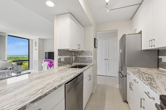 345 W Fullerton Pkwy Unit 1508, Chicago, IL 60614 - kitchen featuring stainless steel appliances, a sink, decorative backsplash, light stone counters, and expansive windows