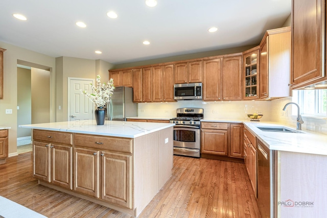 1430 Mcclellan Ct, Lindenhurst, IL 60046 - kitchen featuring appliances with stainless steel finishes, a sink, light wood finished floors, a kitchen island, and glass insert cabinets