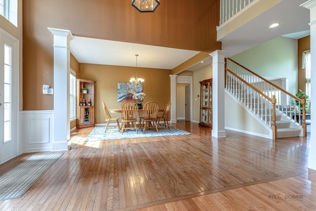 1430 Mcclellan Ct, Lindenhurst, IL 60046 - dining space featuring decorative columns, a towering ceiling, hardwood / wood-style flooring, healthy amount of natural light, and a wainscoted wall