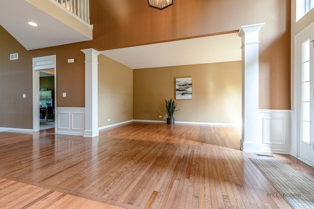 1430 Mcclellan Ct, Lindenhurst, IL 60046 - unfurnished living room featuring ornate columns, hardwood / wood-style floors, a decorative wall, a wainscoted wall, and a high ceiling