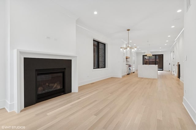 2118 N Sheffield Ave Unit 1, Chicago, IL 60614 - unfurnished living room featuring light wood-style floors, a glass covered fireplace, a chandelier, recessed lighting, and ornamental molding