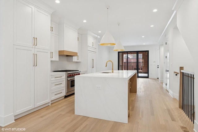 2118 N Sheffield Ave Unit 1, Chicago, IL 60614 - kitchen with premium appliances, light wood-style floors, a kitchen island with sink, white cabinetry, and light countertops