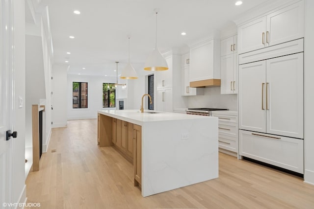 2118 N Sheffield Ave Unit 1, Chicago, IL 60614 - kitchen with paneled fridge, light wood-style floors, an island with sink, recessed lighting, and light countertops