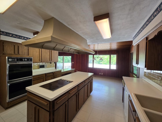 1720 Stratford Ln, Rockford, IL 61107 - kitchen with black appliances, island range hood, light countertops, a kitchen island, and a sink