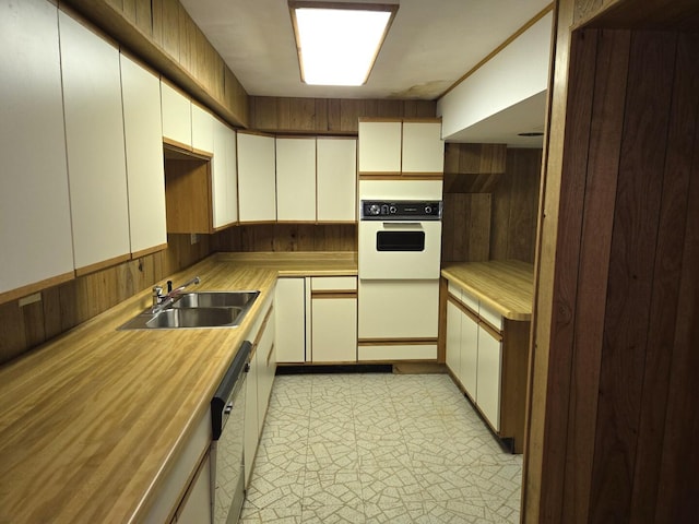 1720 Stratford Ln, Rockford, IL 61107 - kitchen featuring white oven, dishwashing machine, a sink, wooden walls, and white cabinetry