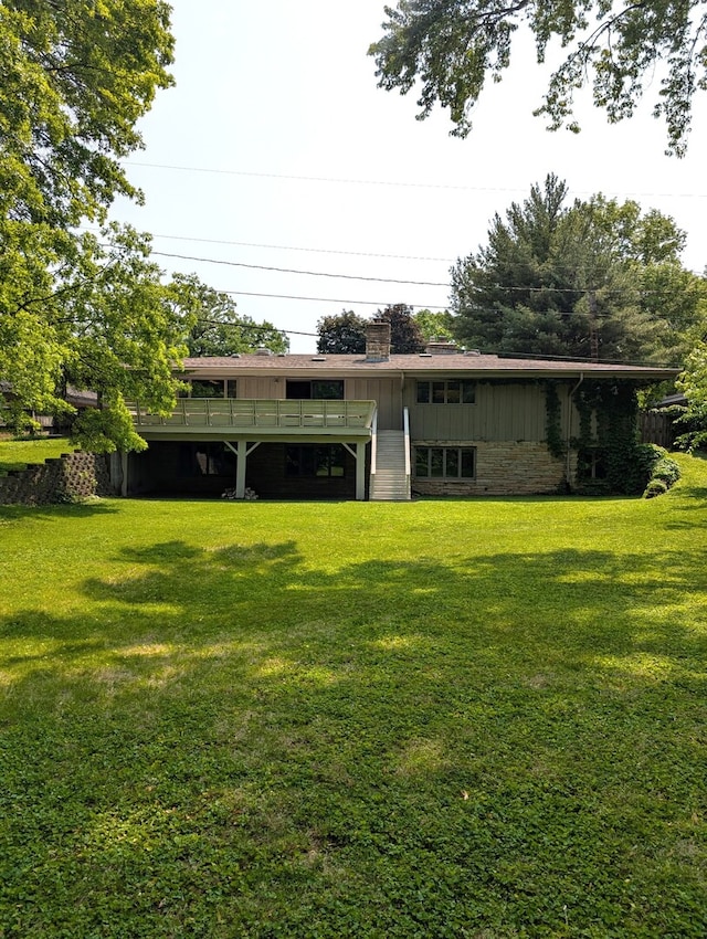 1720 Stratford Ln, Rockford, IL 61107 - back of property with a lawn, a wooden deck, a chimney, and board and batten siding
