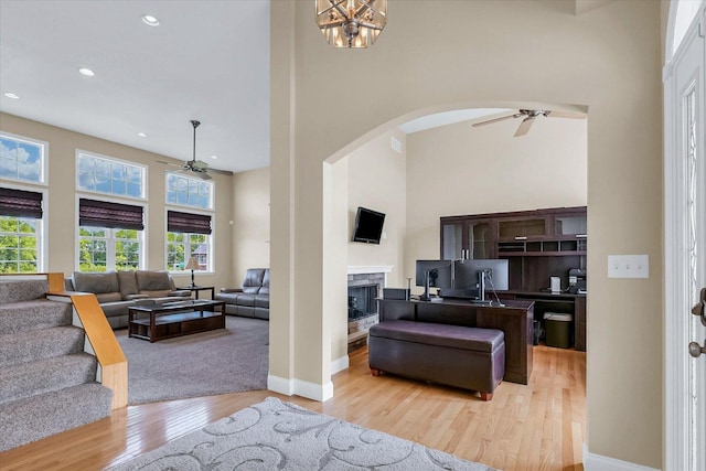 402 Cypress Ct, Saint Joseph, IL 61873 - living area featuring a ceiling fan, a towering ceiling, arched walkways, light wood-style floors, and a high end fireplace