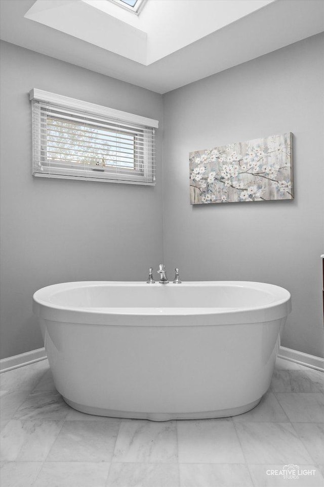 13214 Sunderlin Rd, Plainfield, IL 60585 - bathroom featuring marble look tile flooring, a skylight, baseboards, and a freestanding tub