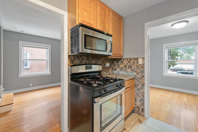 4308 Oak St, Bellwood, IL 60104 - kitchen featuring stainless steel appliances, light wood-style floors, plenty of natural light, and decorative backsplash