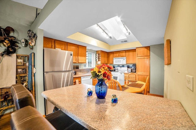 6719 W White Tailed Ln Unit 3E, Tinley Park, IL 60477 - kitchen featuring white appliances, a tray ceiling, a skylight, a kitchen breakfast bar, and light countertops
