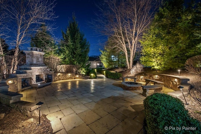 11 Moate Ln, Barrington Hills, IL 60010 - pool at night featuring an outdoor stone fireplace, a patio area, and a fire pit