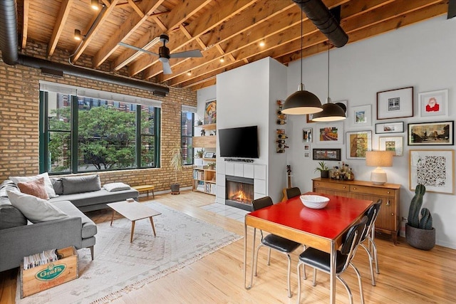 2943 N Lincoln Ave Unit 202, Chicago, IL 60657 - living area with brick wall, a ceiling fan, a tile fireplace, light wood finished floors, and a wood ceiling with exposed beams