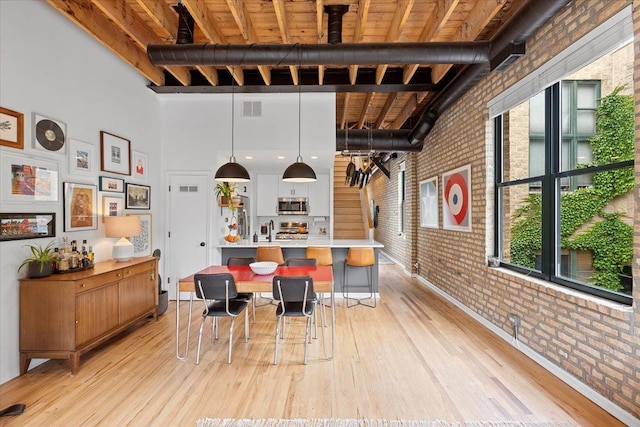 2943 N Lincoln Ave Unit 202, Chicago, IL 60657 - dining space featuring brick wall, light wood-type flooring, a towering ceiling, and a wooden ceiling with exposed beams