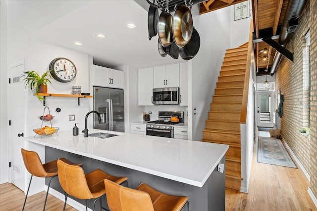2943 N Lincoln Ave Unit 202, Chicago, IL 60657 - kitchen with appliances with stainless steel finishes, a peninsula, open shelves, light wood-style flooring, and a breakfast bar area