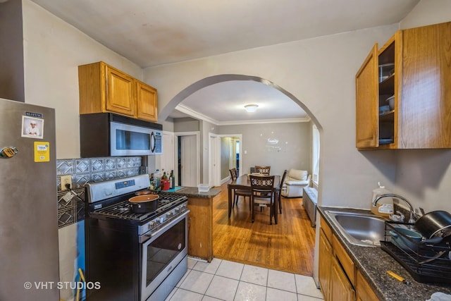 22 S Austin Blvd, Oak Park, IL 60302 - kitchen with appliances with stainless steel finishes, arched walkways, brown cabinets, light tile patterned floors, and dark stone countertops