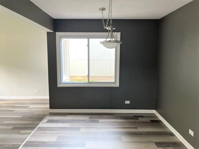 5711 Ring Ct, Hanover Park, IL 60133 - unfurnished dining area with a textured ceiling, wood finished floors, and baseboards