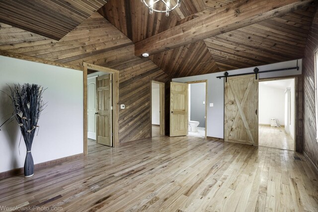 23314 W Liberty Ave, Lake Villa, IL 60046 - unfurnished bedroom featuring a barn door, wooden walls, wood-type flooring, high vaulted ceiling, and baseboards