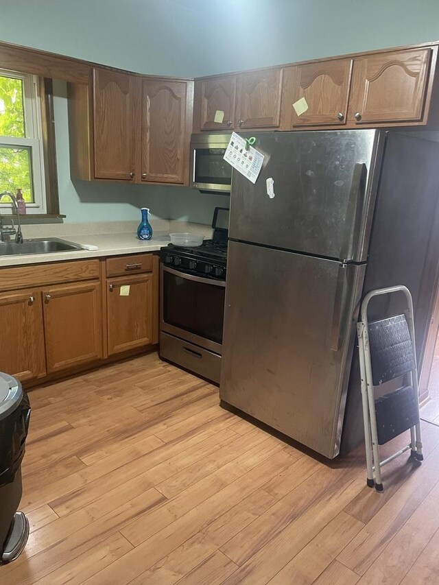 4121 N Moody Ave, Chicago, IL 60634 - kitchen featuring appliances with stainless steel finishes, a sink, light wood-style floors, light countertops, and brown cabinetry
