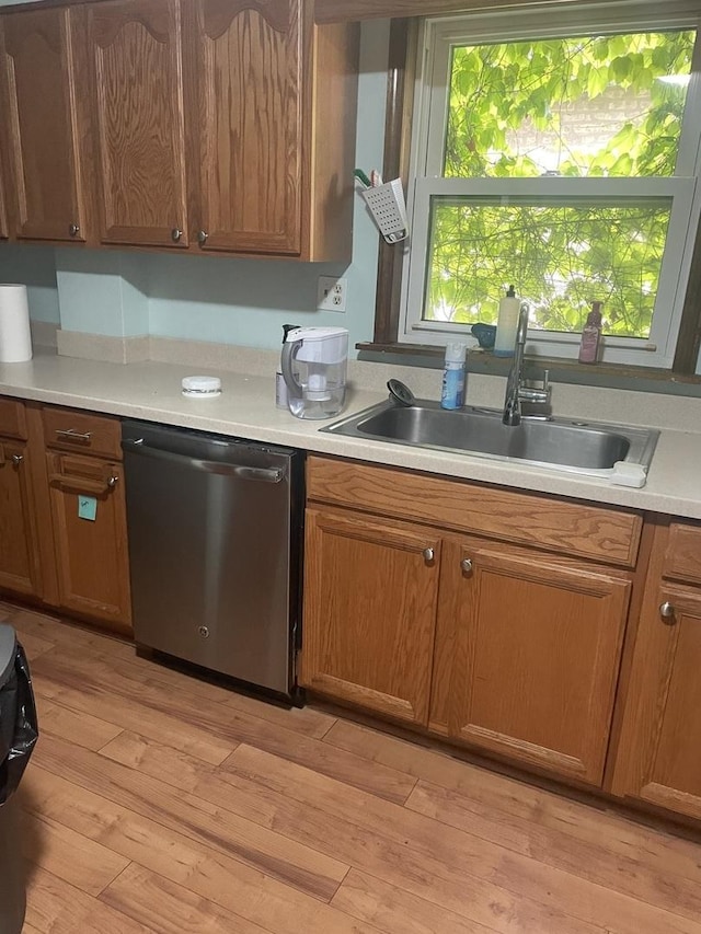 4121 N Moody Ave, Chicago, IL 60634 - kitchen with stainless steel dishwasher, a sink, light countertops, light wood-style floors, and brown cabinetry