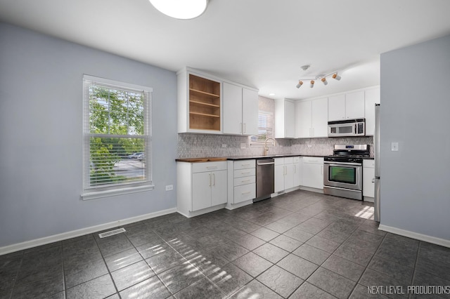 3023 Saganashkee Ln, Naperville, IL 60564 - kitchen featuring stainless steel appliances, backsplash, open shelves, dark countertops, and white cabinets