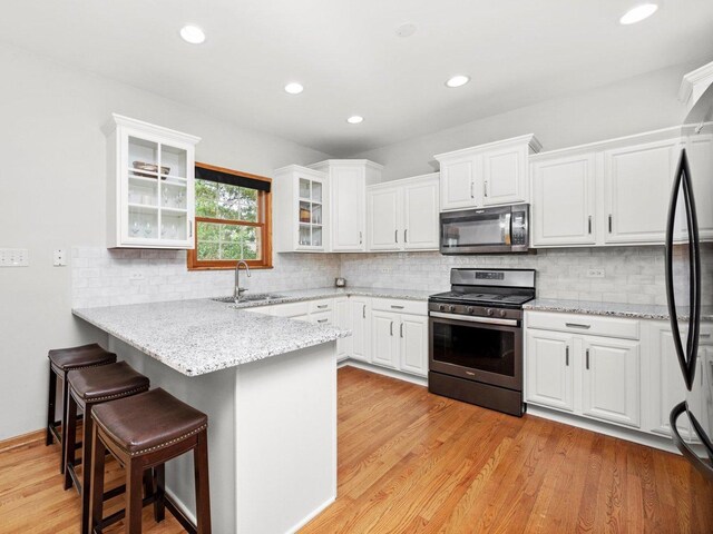 3445 W 114th St, Chicago, IL 60655 - kitchen featuring stainless steel appliances, a peninsula, white cabinets, a breakfast bar, and recessed lighting