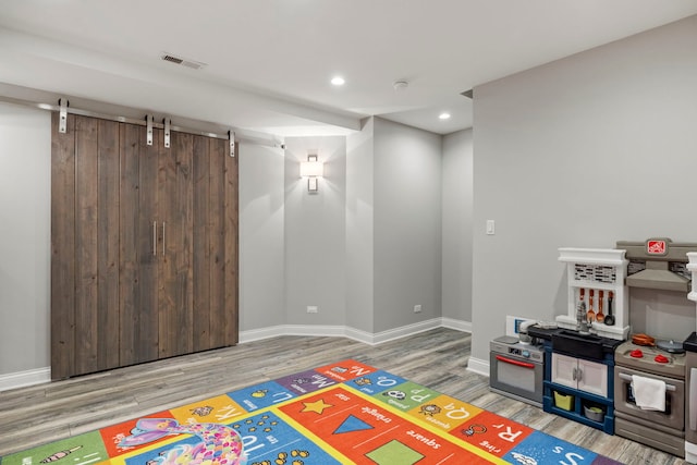 12433 Dublin Ln, Plainfield, IL 60585 - recreation room with wood finished floors, a barn door, baseboards, and recessed lighting