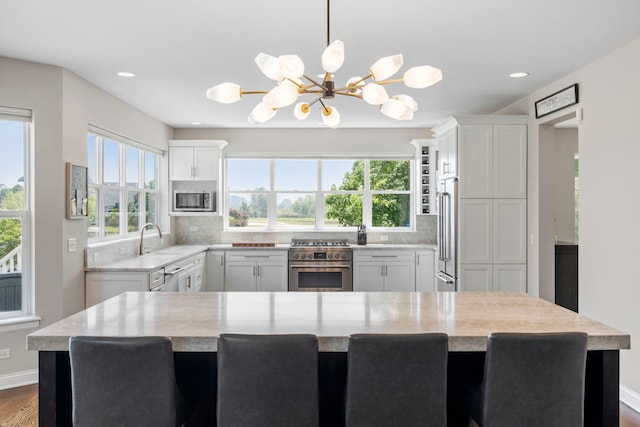 12433 Dublin Ln, Plainfield, IL 60585 - kitchen featuring high quality appliances, a chandelier, a sink, white cabinets, and backsplash