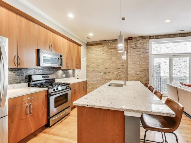 834 N Wood St Unit 2N, Chicago, IL 60622 - kitchen with stainless steel appliances, a sink, a breakfast bar area, light wood-style floors, and brick wall