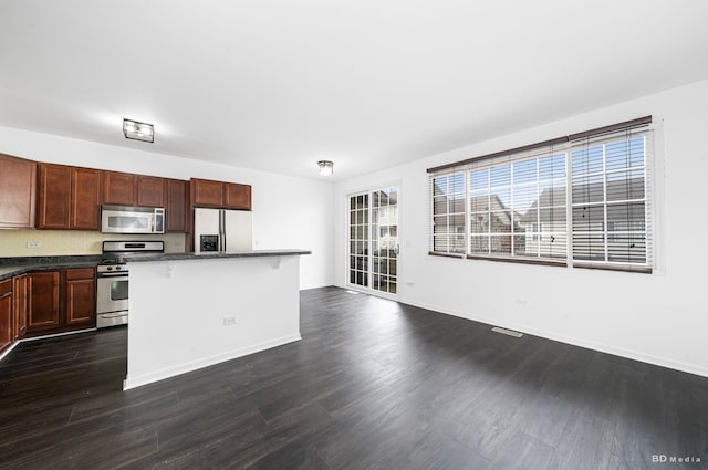 10651 Gabrielle Ln, Orland Park, IL 60462 - kitchen with appliances with stainless steel finishes, a kitchen bar, dark wood-type flooring, a center island, and baseboards