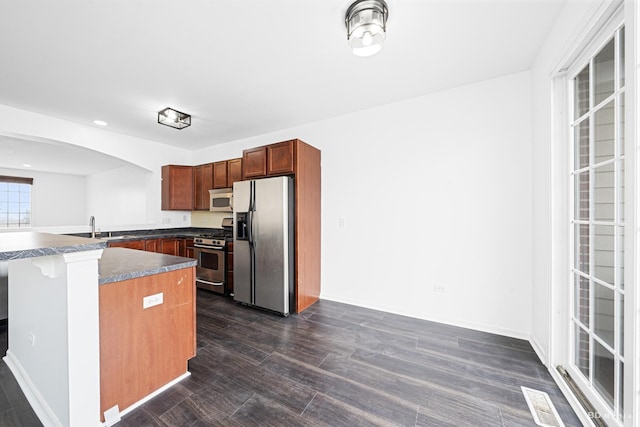 10651 Gabrielle Ln, Orland Park, IL 60462 - kitchen featuring appliances with stainless steel finishes, dark wood finished floors, dark countertops, arched walkways, and recessed lighting