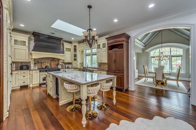 217 Haman Rd, Inverness, IL 60010 - kitchen with a chandelier, cream cabinetry, custom range hood, a kitchen island with sink, and dark wood-style flooring