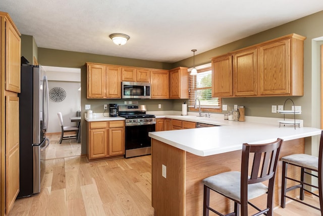 5804 Targee Trl, Roscoe, IL 61073 - kitchen featuring stainless steel appliances, a sink, a peninsula, light wood finished floors, and a breakfast bar area