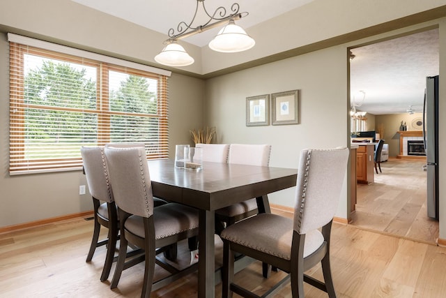 5804 Targee Trl, Roscoe, IL 61073 - dining room featuring light wood finished floors, baseboards, a chandelier, and a glass covered fireplace
